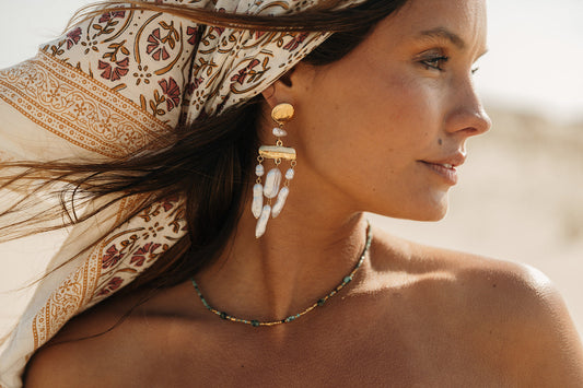 Inspiration tenue de réveillon femme : bijoux dorés et style bohème sur la plage.