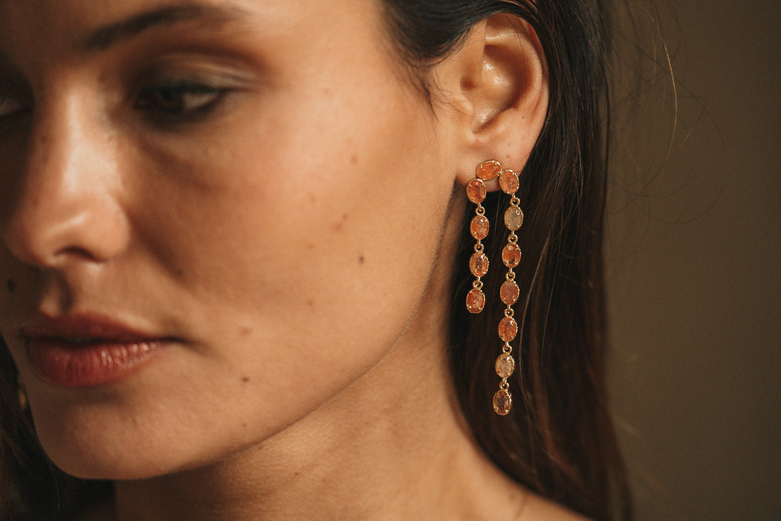 Gros plan d’une femme portant des boucles d’oreilles dorées en acier inoxydable, symbole d’élégance et de confort pour les peaux sensibles.