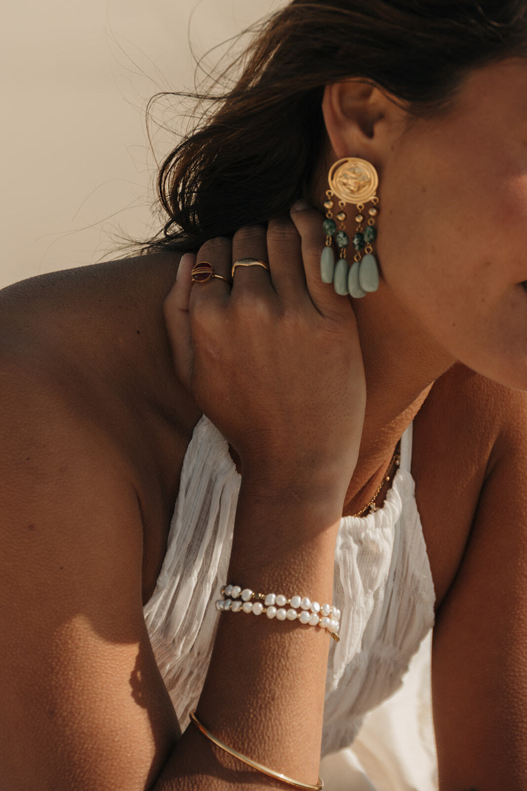 Bijoux pour accessoiriser une robe noire : boucles d’oreilles dorées et bracelets délicats.