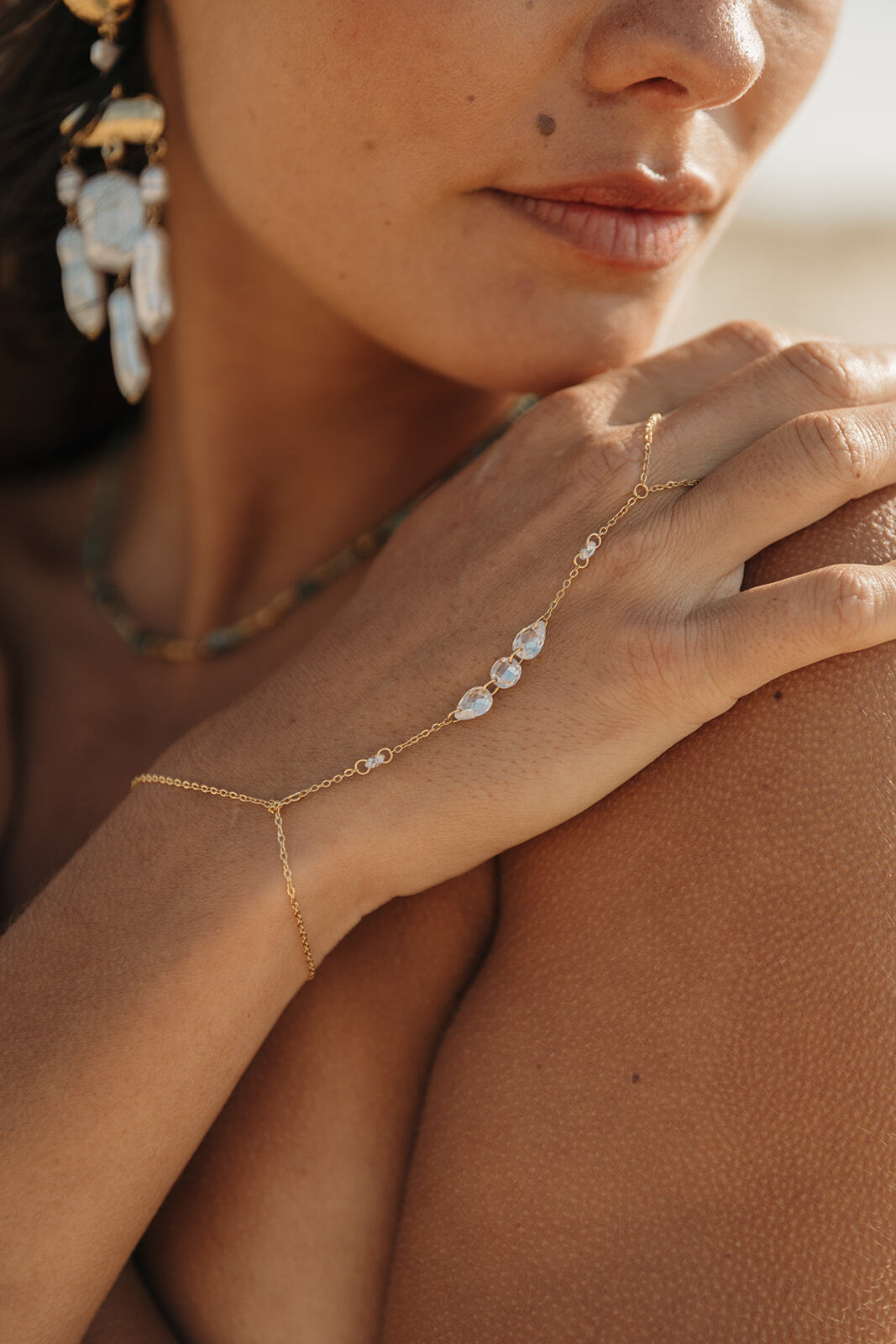 Chaîne de main en acier inoxydable, bijou fin avec perles blanches porté au poignet.