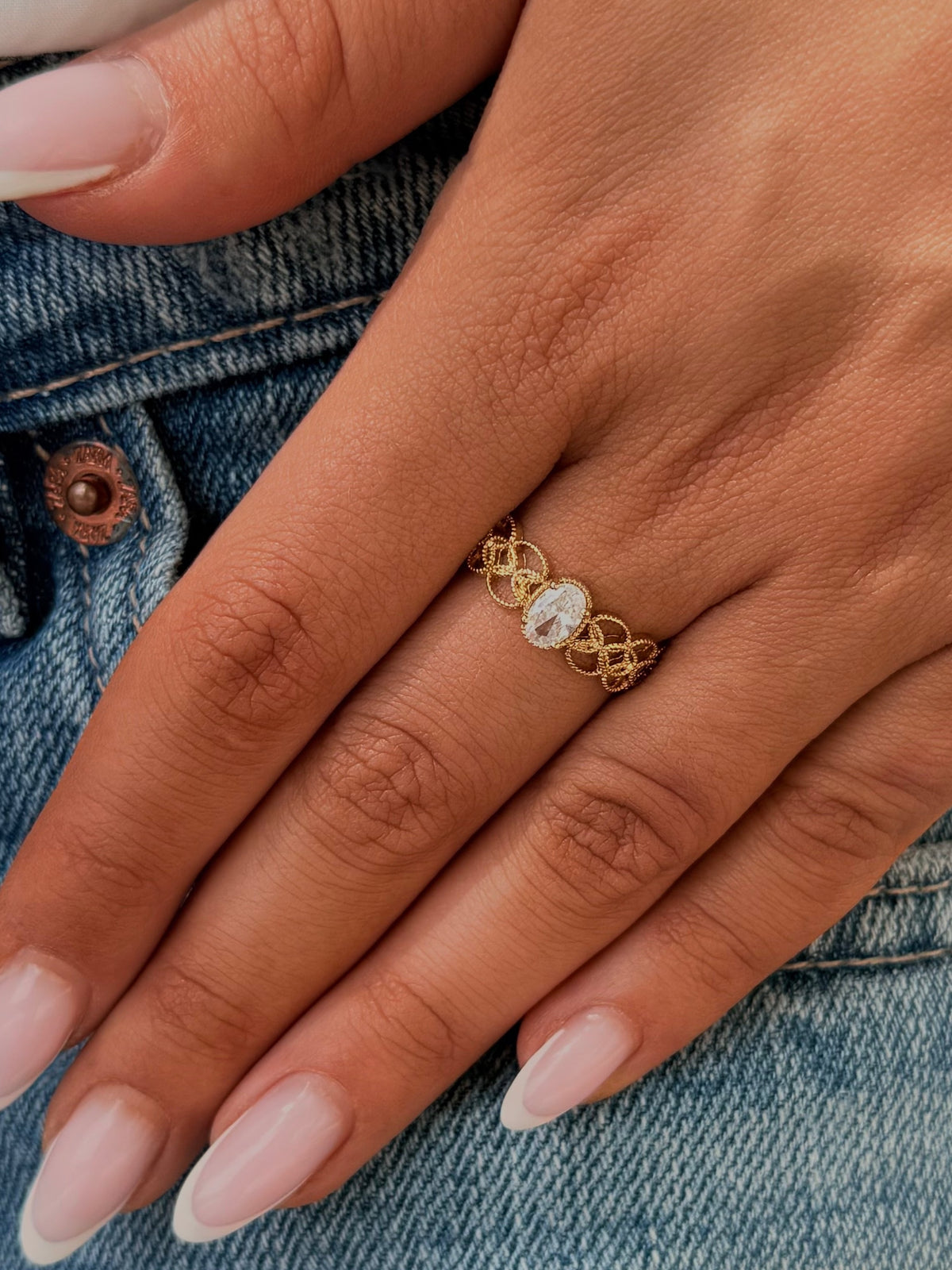 Bague CHIARA dorée ajourée avec strass ovale, portée à l'annulaire – gros plan